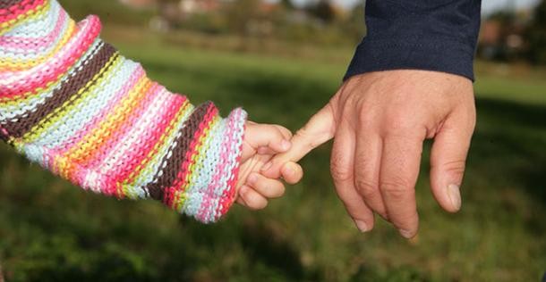 Kinderhand hält sich an Erwachsenenhand fest 