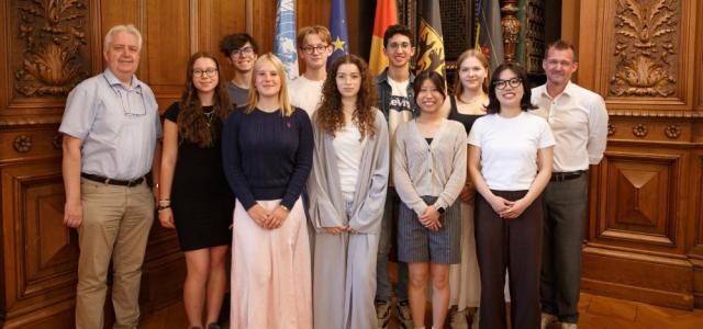 Dr. Bernold Feuerstein posiert mit Bürgermeister Raoul Schmidt-Lamontain und den Teilnehmenden der International Summer Science School für die Kamera.