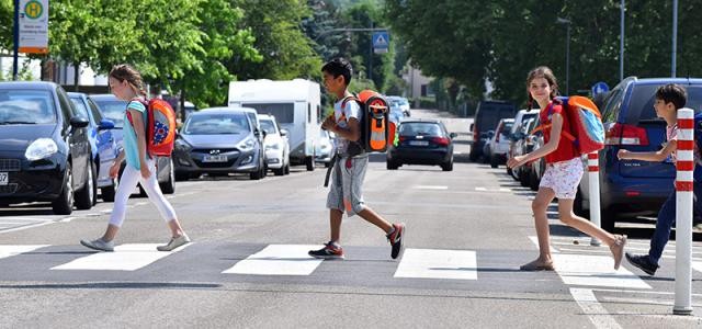 Kinder überqueren an einem Zebrastreifen eine Straße