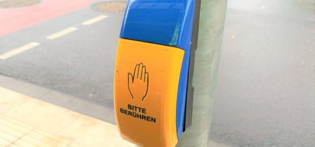 Anforderungstaste einer Ampelanlage für Fußgänger, mit einer abgebildeten Hand und der Aufschrift "Bitte berühren".