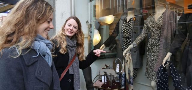 Zwei Frauen schauen in ein Schaufenster, in dem Mode sichtbar ist.