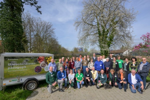 Teilnehmerinnen und Teilnehmervor einem Baum und neben einem LKW-Anhänger mit Aufschrift bei der Programmeröffnung von „Natürlich Heidelberg 2024“