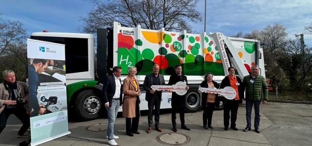 Sieben Personen stehen vor einem bunt beklebten Müllauto.