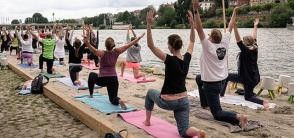 Menschen machen Yoga-Übungen an einem künstlichen Sandstrand am Neckar. 