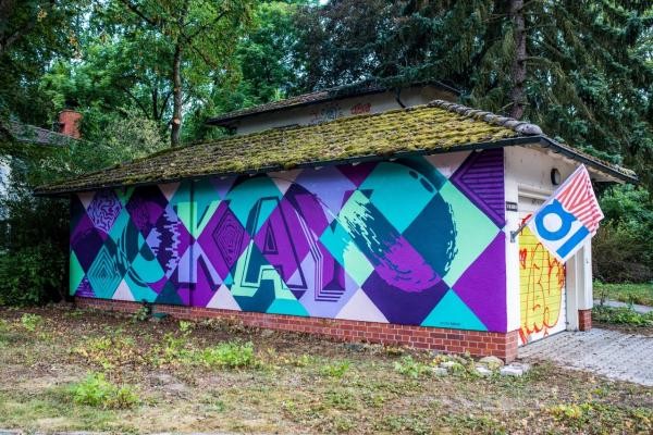Die Wand einer Garage wurde mit dem Wort Okay und einem Karomsuter in den Farben Lila und Türkis bemalt. (Foto: IBA/Dittmer)
