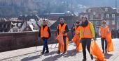 Mehrere Personen in orangefarbenen Westen und Müllbeuteln laufen über die Alte Brücke (Foto: Dorn)