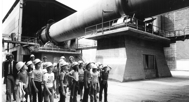 Viele Kinder mit Schutzhelmen schauen hoch zu einem sehr großen Fabrikrohr (Foto: Elfriede Winterer)