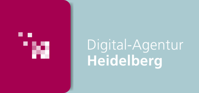 Zwei Laptops stehen auf einem Tisch, zwischen ihnen liegen Notizen und Kabel.