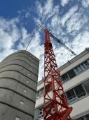 Blick von unten auf den Baukran mit einem Feuerwehrmann, der diesen gesgesichert hochsteigt