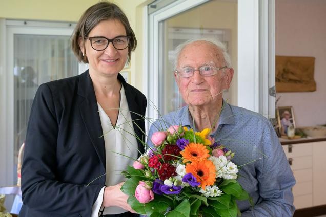 Eine Frau und ein älterer Herr posiern mit einem Blumenstrauß.