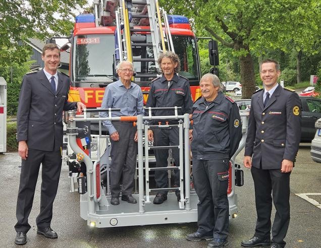 Einige Feuerwehrleute posieren auf der Drehleiter eines Feuerwehrfahrzeuges.