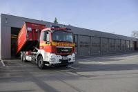 Feuerwehr-LKW lädt einen Abrollbehälter in der neuen Halle ab.