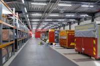 Blick in die Halle mit einem Regal links und rechts stehen Abrollbehälter.