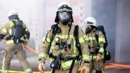 Ein Feuerwehrmann der eine Atemschutzmaske aufgesetzt hat schaut in die Kamera