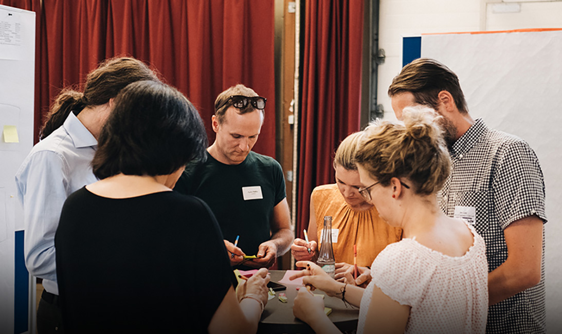 Weiterbildung und Workshops für Kreative. (Foto: Beekmann) Mehrere Menschen stehen um einen Tisch.