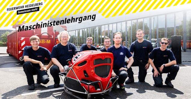 Gruppenaufnahme der Lehrgangsteilnehmer, die sich neben einer tragbaren Feuerwehrpumpe auf den  Boden knieenn