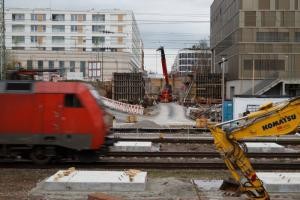 Bild der Baustelle der Gneisenaustraße, während davor ein Zug auf der Strecke fährt.