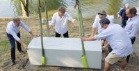 Ein Kran hebt einen großen Betonblock auf seinen Platz. Vier Männer in Hemden helfen dabei. (Foto: Mezger)