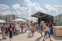Fest in der Bahnstadt (Foto: Buck) Viele Leute sind auf einem Platz. Auf diesem Platz ist eine Bühne aufgebaut und es gibt Sonnenschirme (Foto: Buck)