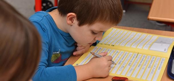 Erstklässler sitzt am Schultisch und übt schreiben (Foto: Dorn)