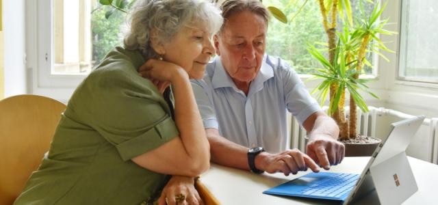 Zwei Senioren arbeiten an einem Laptop.