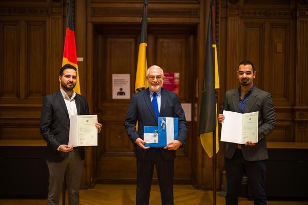 Arkan Müller (l.) und Suliman Abu Ghaida (r.) präsentieren zusammen mit Bürgermeister Wolfgang Erichson stolz ihre Einbürgerungsurkunden. 