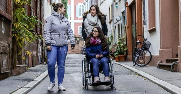 Mobil-AtLaS: Ein Routen-Planer in einfacher Sprache (Foto: Pellner) Eine junge Frau schiebt eine andere Frau im Rollstuhl und eine dritte junge Frau läuft neben ihnen (Foto: Pellner