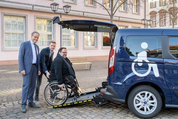 Ein Rollstuhlfahrer wird ins Rollstuhltaxi geschoben