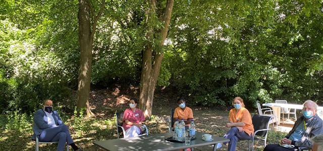 Oberbürgermeister Würzner sitzt mit Pflegekräften um einen Tisch im Garten. (Foto: Stadt Heidelberg)
