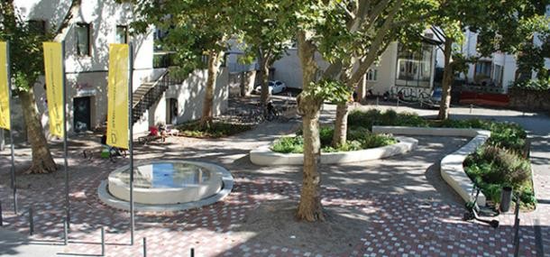 Neu gestalteter Theaterplatz mit Brunnen und Bäumen. 