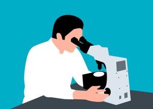 Ein Mann sitzt an einem Mikroskop und schaut durch das Okular.