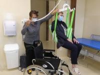 Frau Reiß hebt eine Dame aus dem Rollstuhl mit dem mobilen Lifter auf eine Liege.Foto: Landesverband für Menschen mit Körper- und Mehrfachbehinderten Baden-Württemberg e.V. Frau Reiß hebt eine Dame aus dem Rollstuhl mit dem mobilen Lifter auf eine Liege.