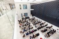 Im Foyer des EMBL Imaging Centres sitzen Leute in Stuhlreihen zusammen.