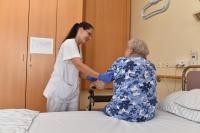 Die Zahl der älteren Menschen mit Pflegerisiko wird in den kommenden Jahren auch in Heidelberg zunehmen. (Foto: Peter Dorn) Eine alte Dame sitzt auf dem Bettrand, vor ihr ein Rollator und eine Altenpflegerin hilft ihr beim Aufstehen.