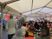 Ein kleines Grillfest zu sechs Jahren Ausbildungshaus gab es in einem Zelt vor dem Gebäude in der Südstadt. (Foto: Heidelberger Dienste) Menschen sitzen in einem kleinen Festzelt.