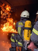 Ablöschen von Flammen Ein Feuerwehrmann löscht Flammen, die von den Gasbrennern erzeugt werden