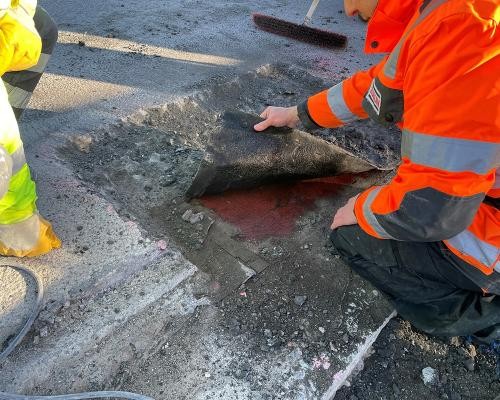 Undichte Fahrbahndecke (Foto: Stadt Heidelberg) Bauarbeiter hebt Straßenbelag an
