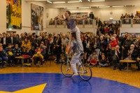 Mitglieder des Kinder- und Jugendcircus Peperoni e.V. bei einer Showeinlage. Eine Person fährt Fahrrad, während die andere obendrauf balanciert.