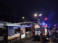 Löschmaßnahme über Dach des Feuerwehrfahrzeugs Auf dem Dach eines Löschfahrzeugs knien zwei Feuerwehrmänner und löschen das Feuer auf dem Dach der gegenüberstehenden Straßenbahn