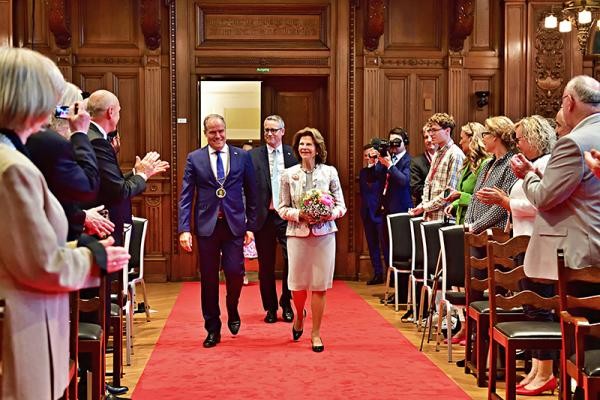 Oberbürgermeister Würzner und Königin Silvia laufen über den Roten Teppich im Rathaussaal.