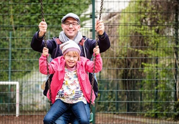 Vater und Kind auf der Schaukel. (Foto: Andi Weiland - Gesellschaftsbilder.de) Ein Vater schaukelt gemeinsam mit seinem Kind. Das Kind sitzt auf dem Schoß.