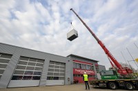 Anlieferung des leistungsstarken Notstromaggregats an das Feuerwehrhaus der Freiwilligen Feuerwehr Kirchheim: Mit einem Autokran wurde der Container über das Gebäude gehoben. (Foto: Rothe) Kran hebt Notstromaggregat in die Luft.