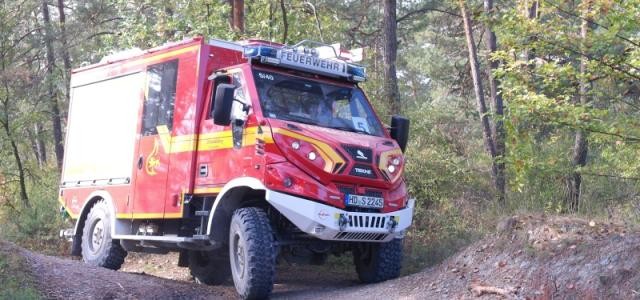 Ein Feuerwehrfahrzeug fährt auf eine Buckelpiste durch den Wald