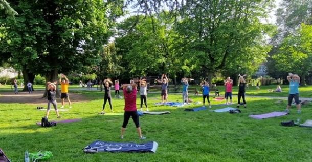 Sport im Park im Grahampark (Foto: Stadt Heidelberg) Menschen auf grüner Wiese strecken die Arme in die Luft