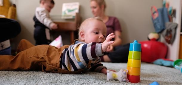 Baby in Bauchlage beim Spielen mit buntem Stapelturm