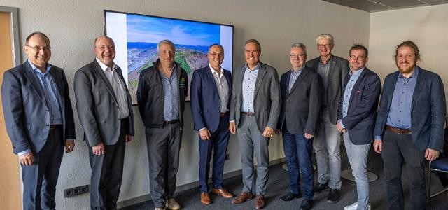 Gruppenfoto in einem Raum vor einer Leinwand
