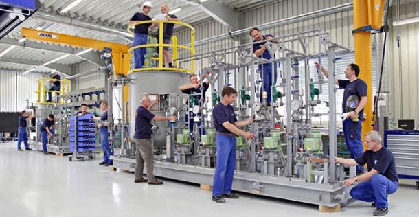 Heidelbergs Unternehmen sind leistungsstark und international (Foto: ProMinent) Fabrikhalle mit Männern, die an einem Dosiersystem von ProMinent arbeiten