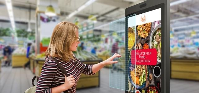 Eine Frau steht vor einem Display und steuert es mit Gesten.