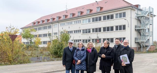 Im Gebäude im Hintergrund wird künftig iWerkx zuhause sein. Investor Dr. Friedrich Hoepfner stellte das Projekt gemeinsam mit Aline Moser (Amt für Wirtschaftsförderung), Stadtdirektorin Nicole Huber, Oberbürgermeister Prof. Dr. Eckart Würzner, Marc Massoth (Leiter Amt für Wirtschaftsförderung) und Georg Breithecker (Geschäftsführer Entwicklungsgesellschaft Patton Barracks, von links) vor. (Foto: Rothe)