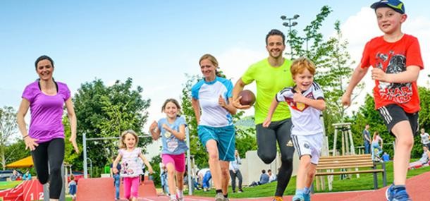 Erwachsene und Kinder beim gemeinsamen Sport machen auf einem Sportplatz. 